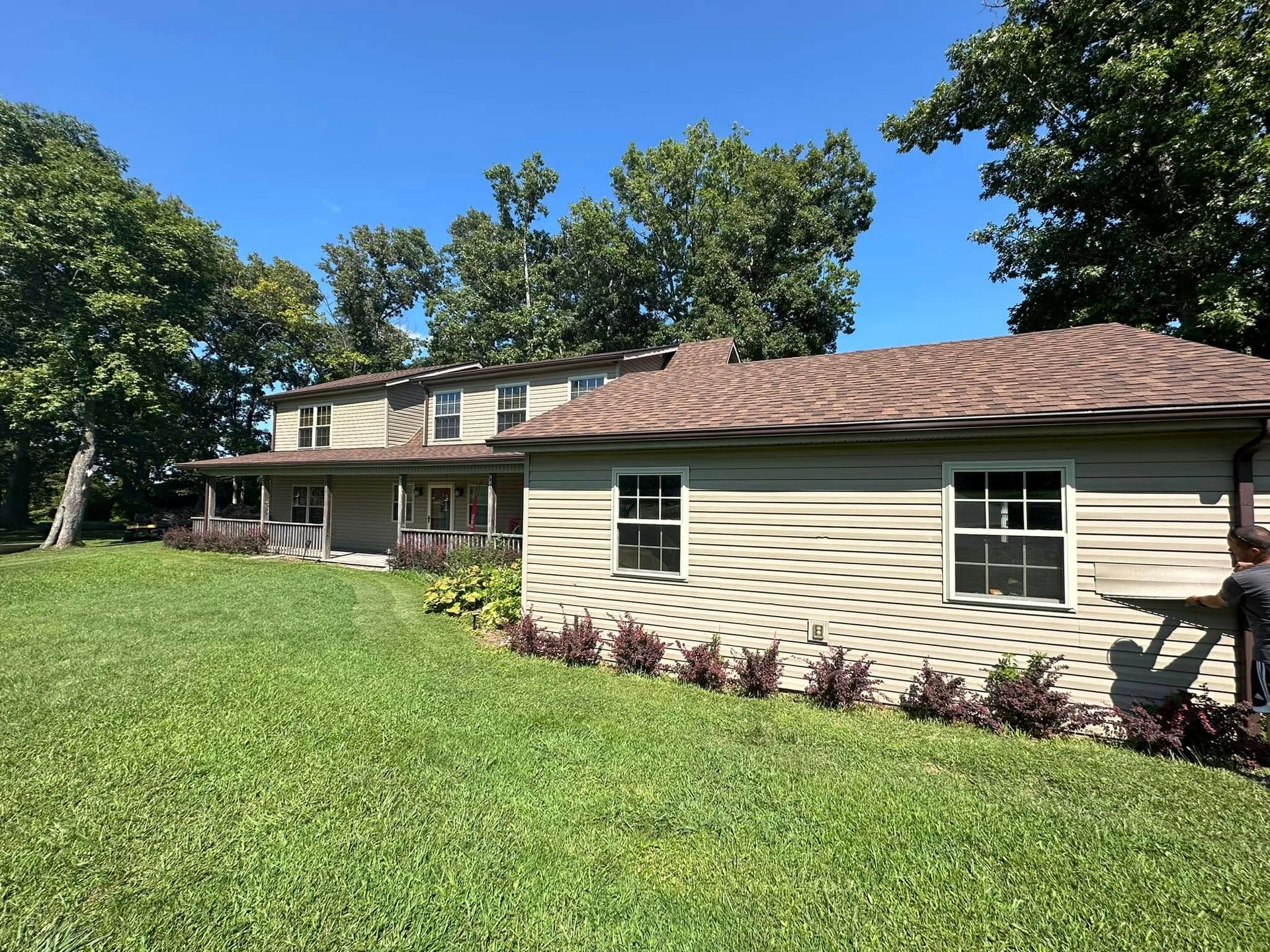 A large house with a lot of windows is sitting on top of a lush green field.
