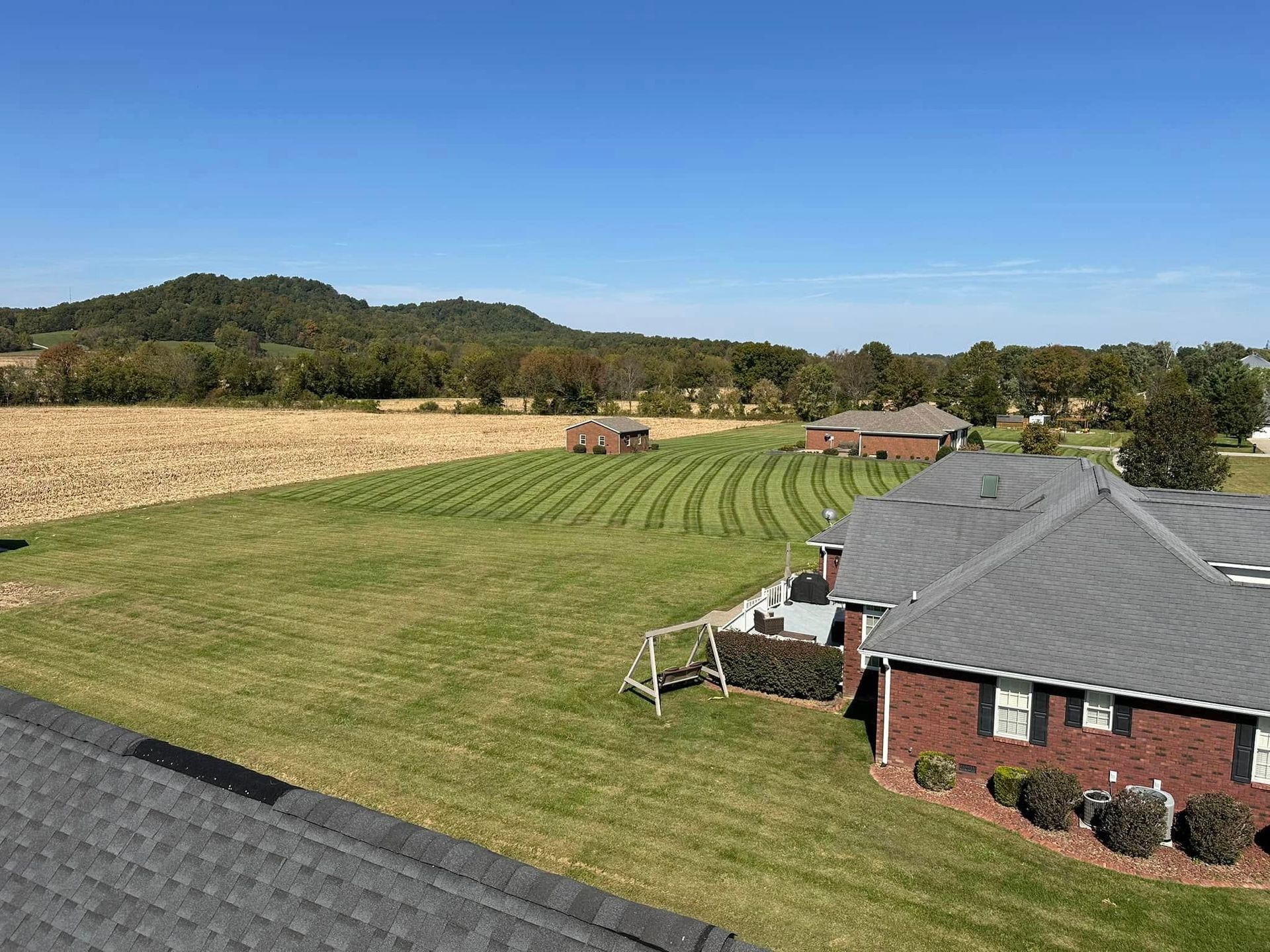 An aerial view of a house in the middle of a lush green field.