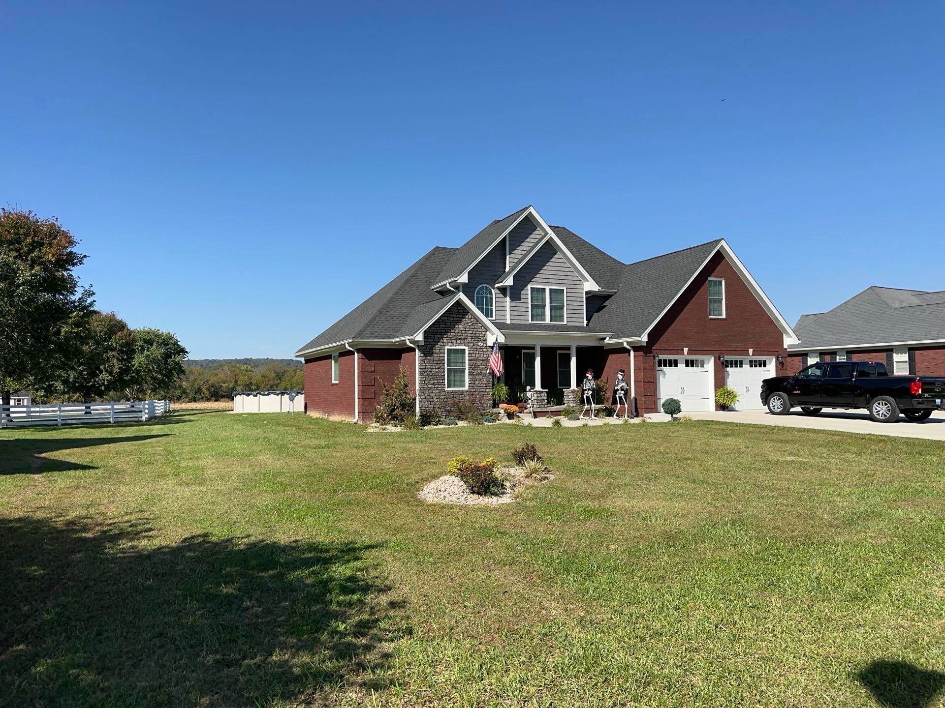 A large brick house with a black truck parked in front of it.