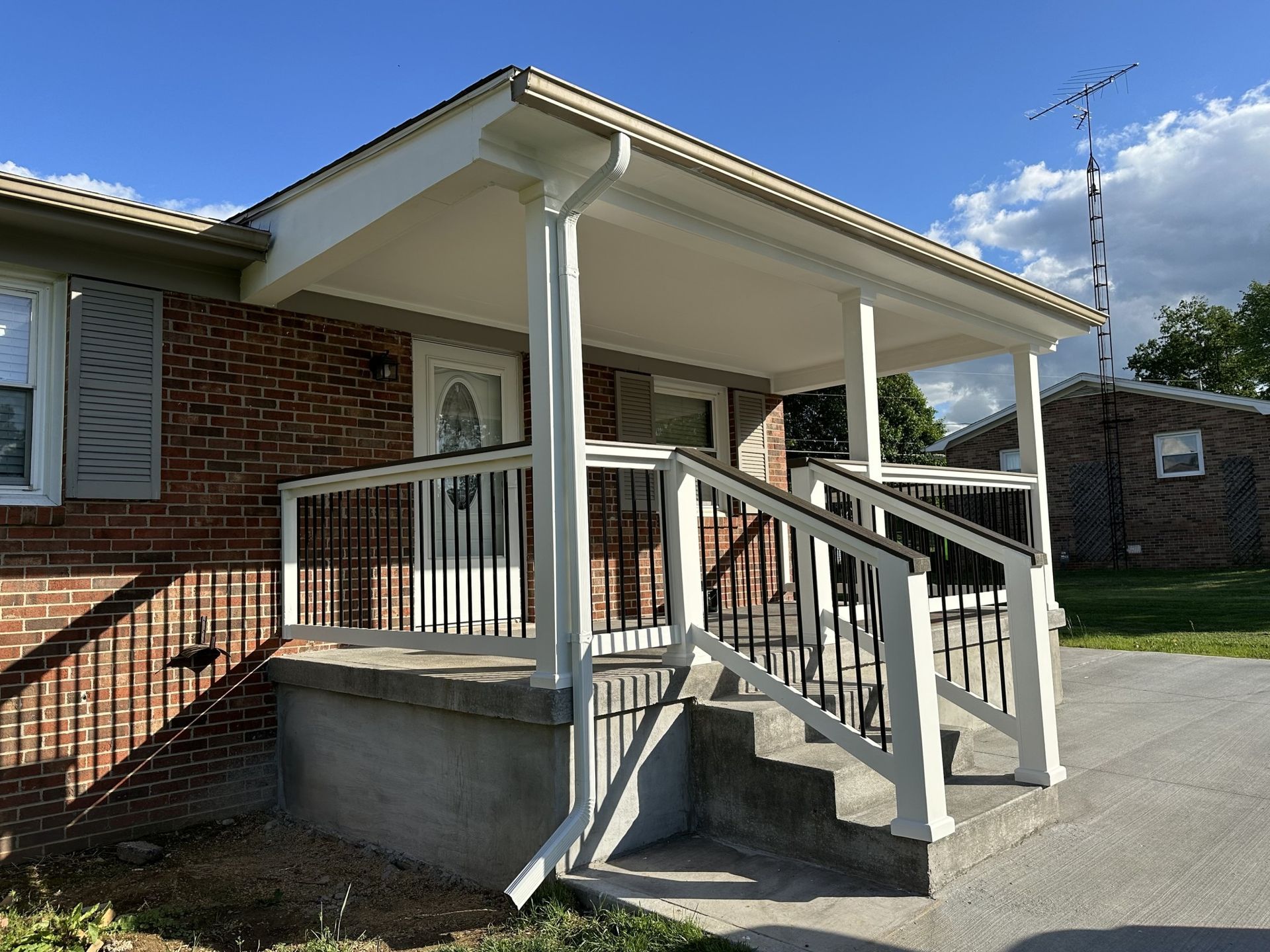 A brick house with a white porch and stairs