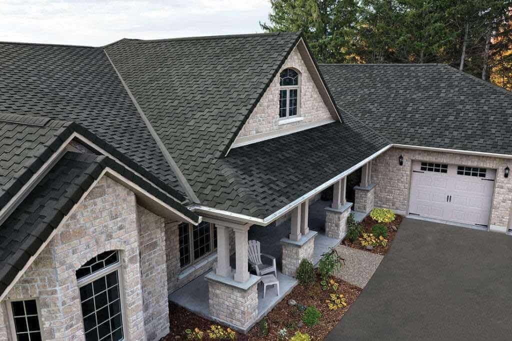 A large brick house with a black roof and a porch.