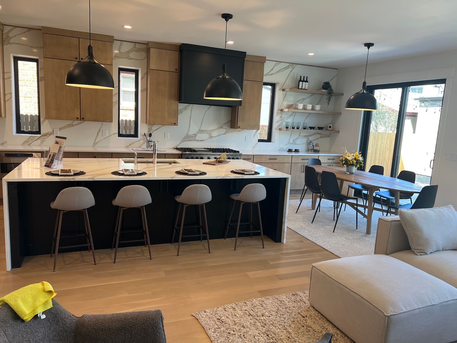 Modern kitchen with island seating, dining area, and marble backsplash.