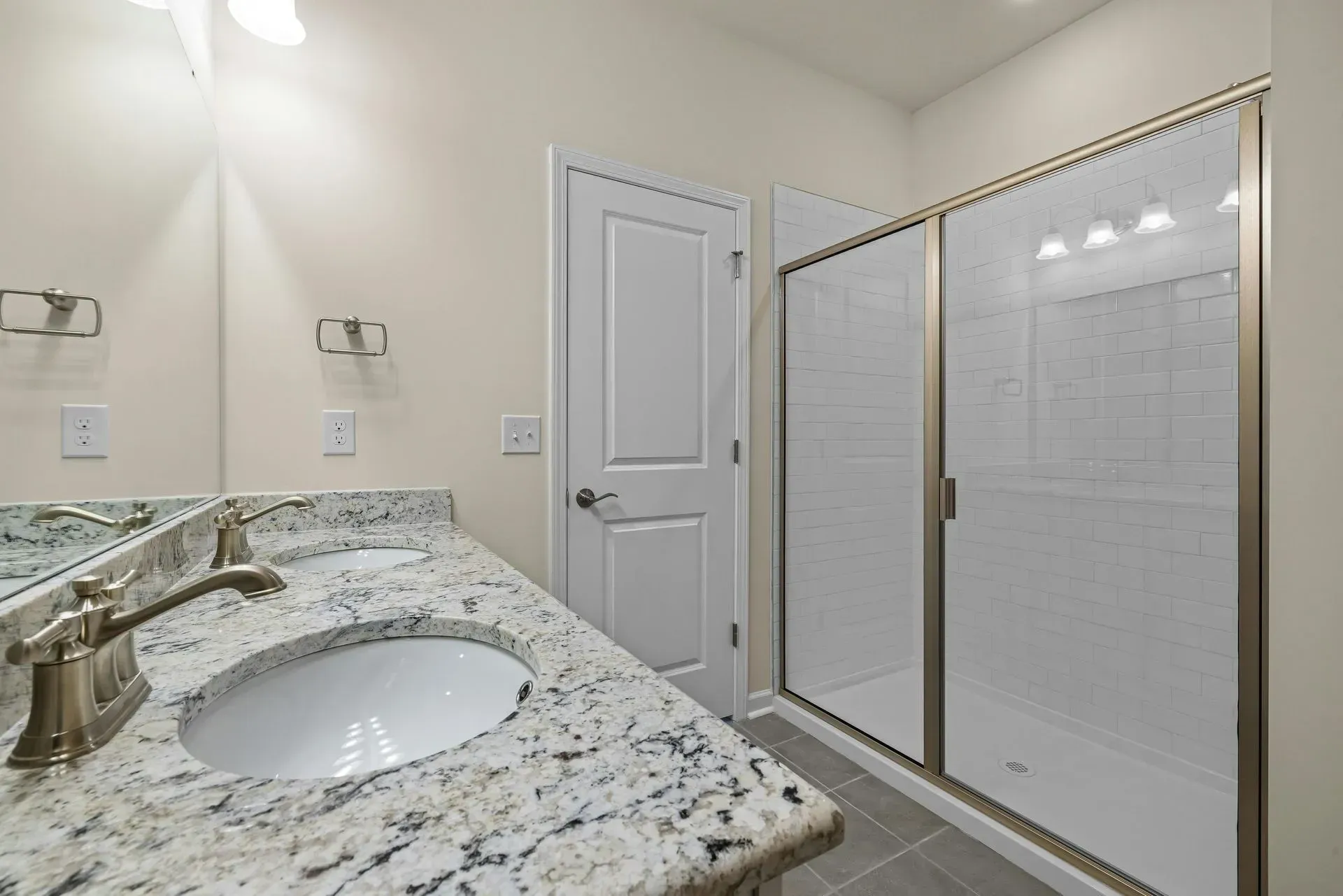 Bathroom with a double vanity, granite countertop, and a glass-enclosed shower.