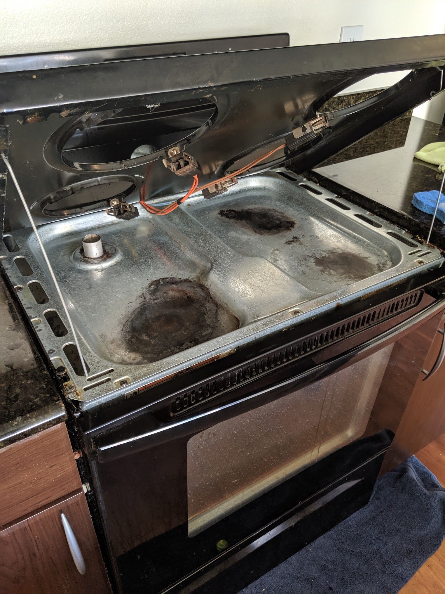 Dirty black oven range with open top, visible cooktop with food residue and the oven door open.