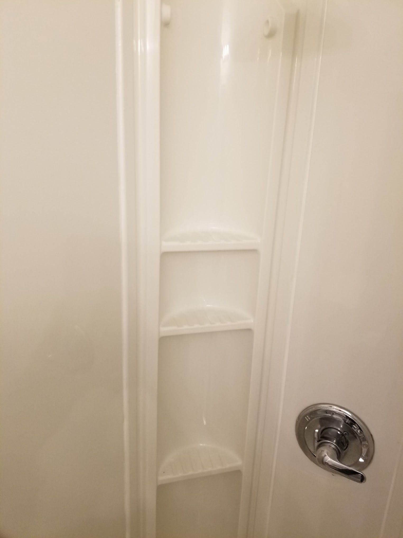 White shower stall with built-in shelves and a chrome faucet.