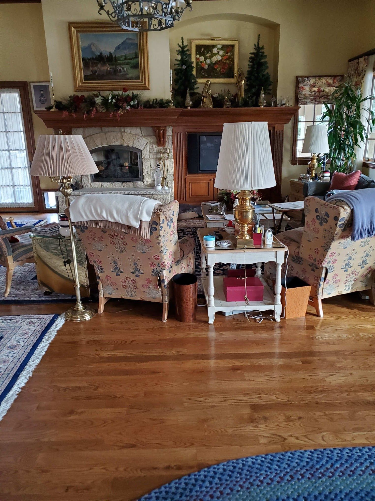 Living room with floral chairs, fireplace, lamps, and wooden floors.
