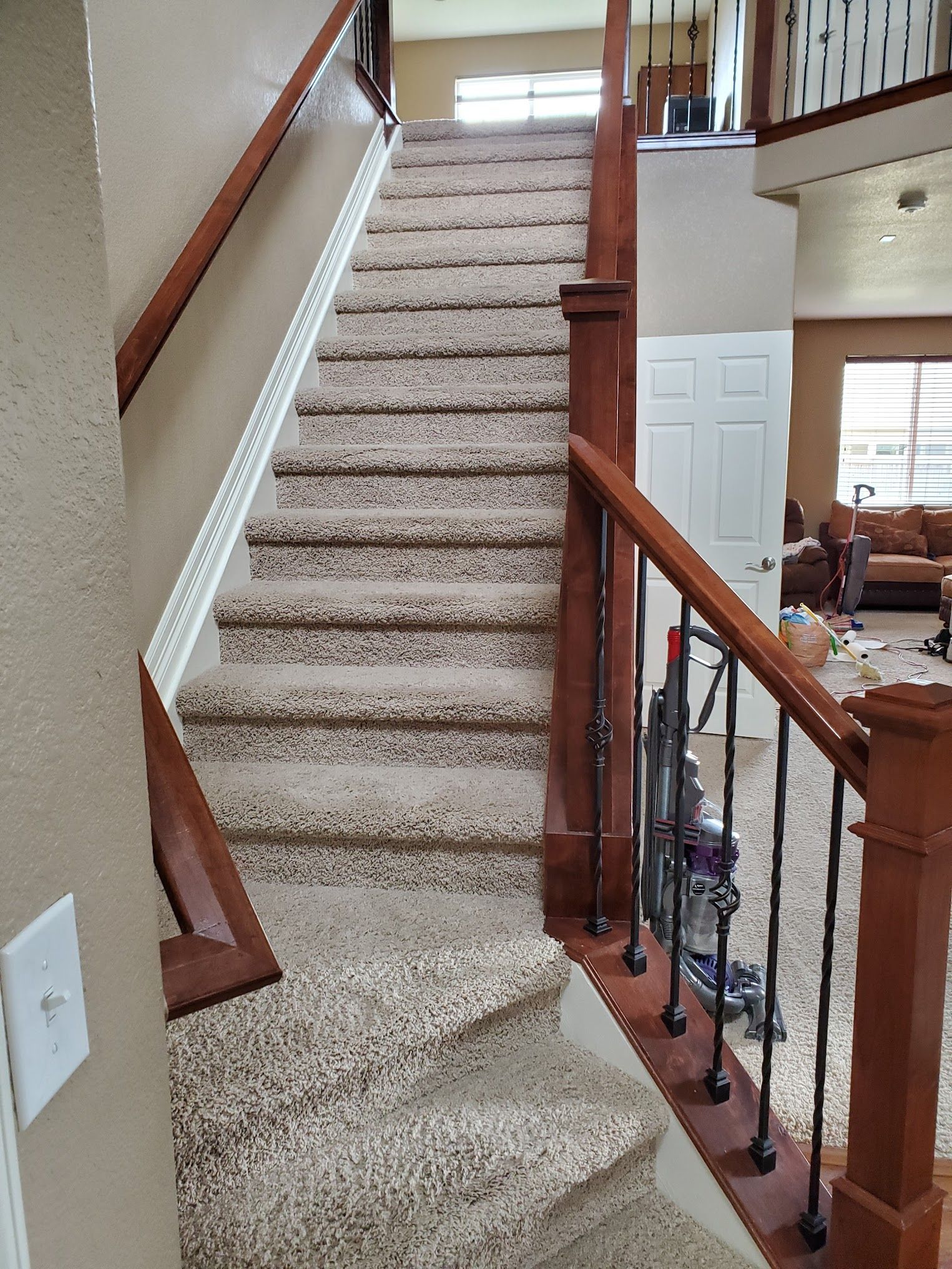 Staircase with carpeted steps, wooden banisters, and a light switch on the wall.