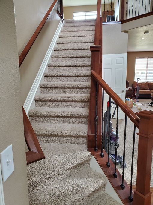 Staircase with carpeted steps, wooden banisters, and a light switch on the wall.