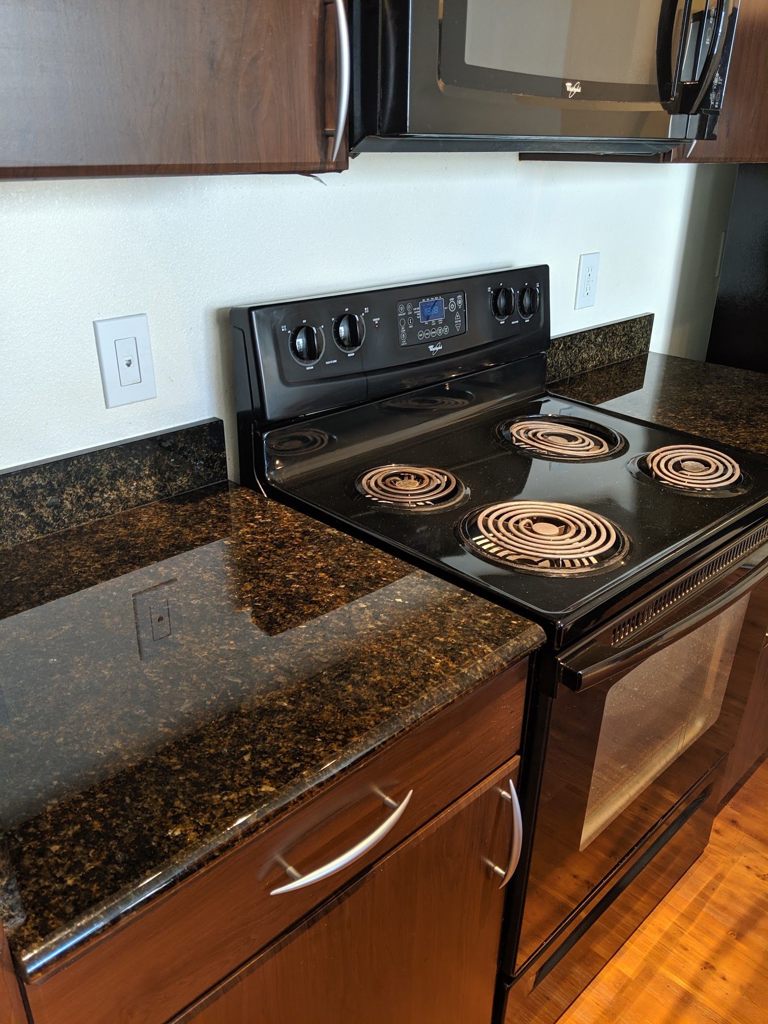 Black electric stove and dark granite countertops in a kitchen.