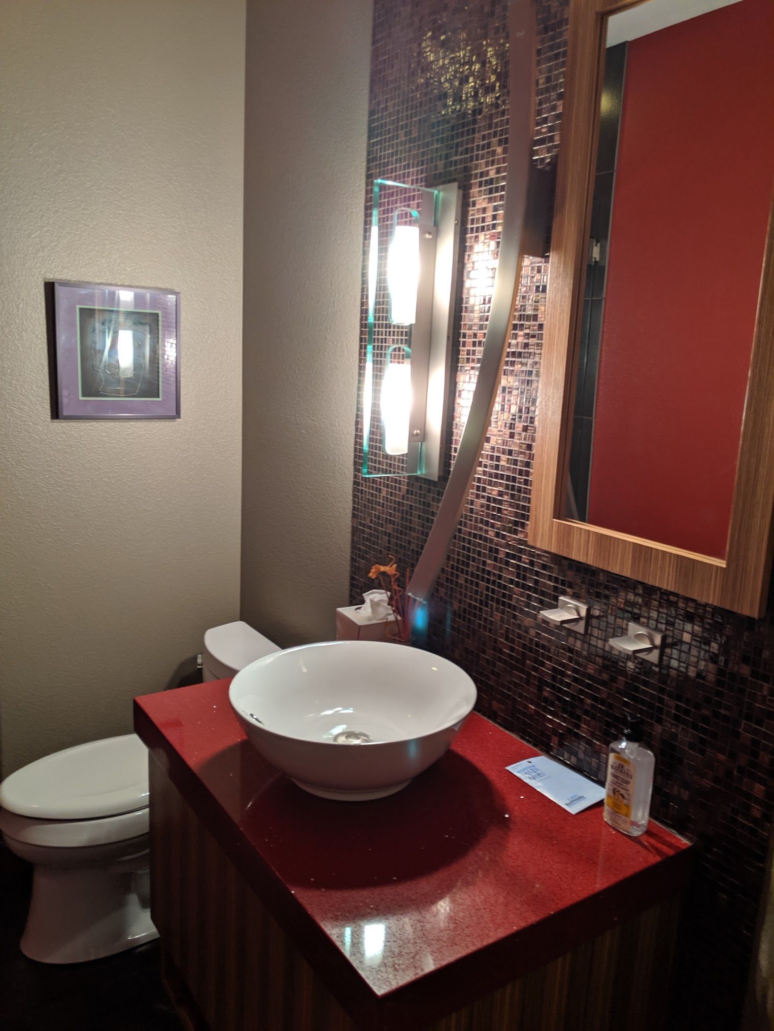 Small bathroom with a vessel sink, red countertop, mosaic tile accent wall, and a mirror.