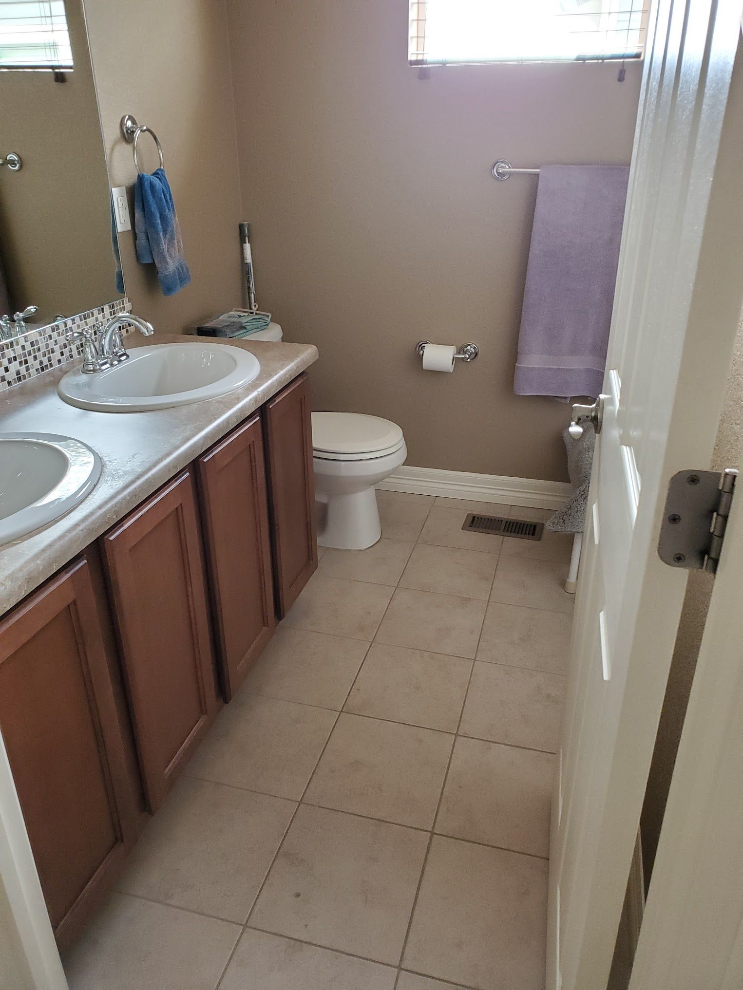 Bathroom with brown cabinets, white sink, toilet, and beige tile floor.