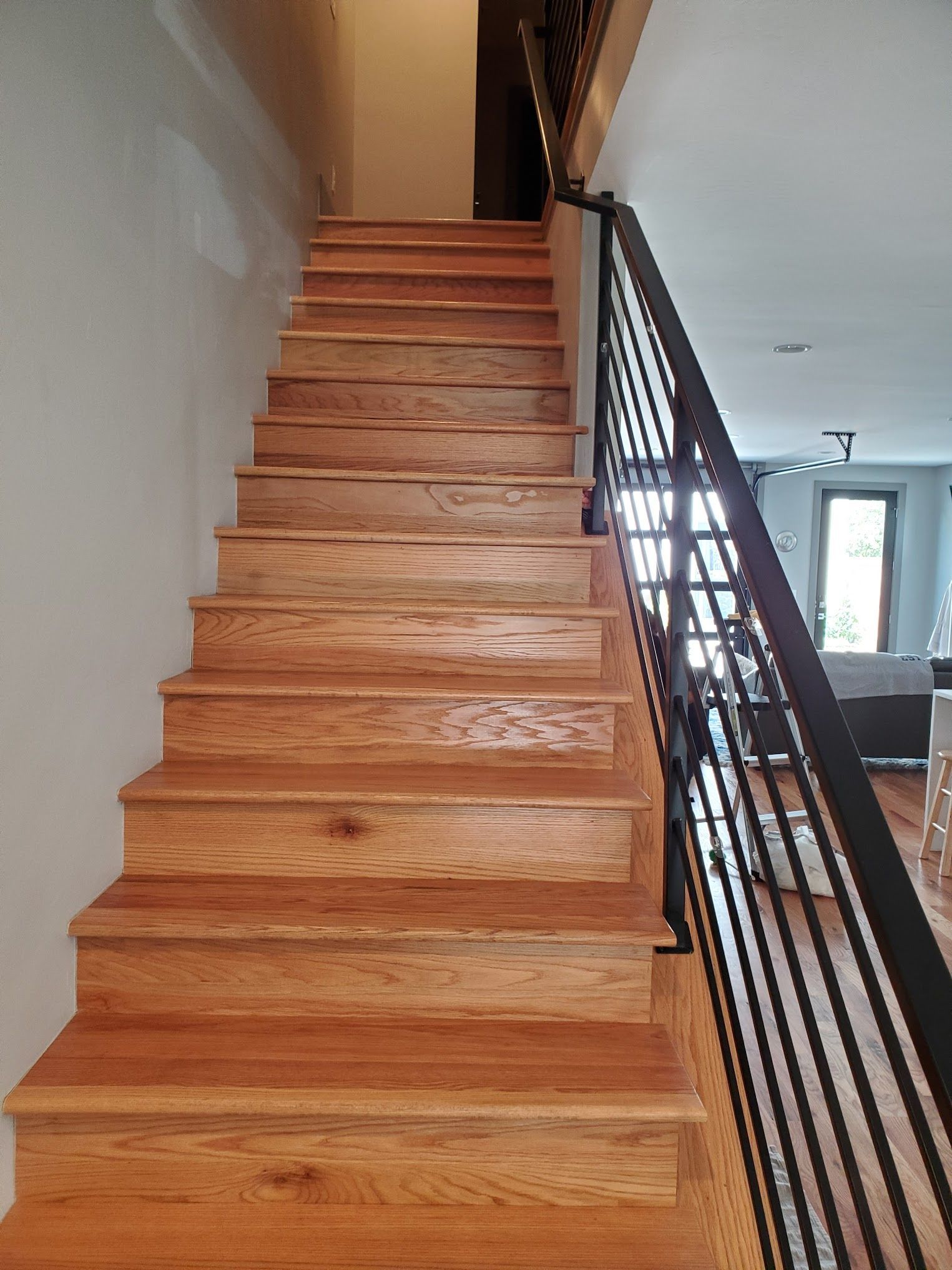 Wooden staircase with black metal handrail leading up to a second floor.