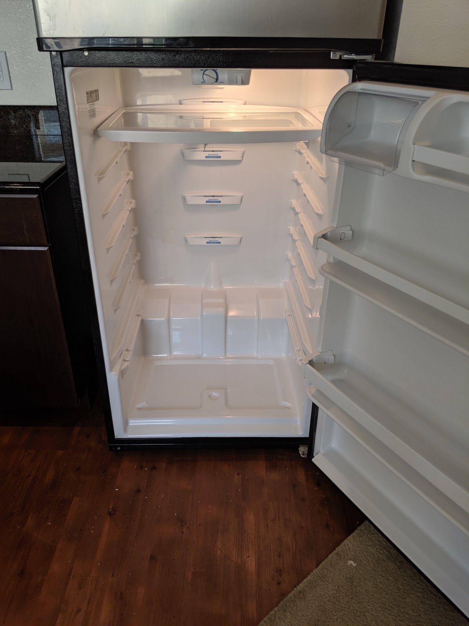 An empty refrigerator with its door open in a kitchen.