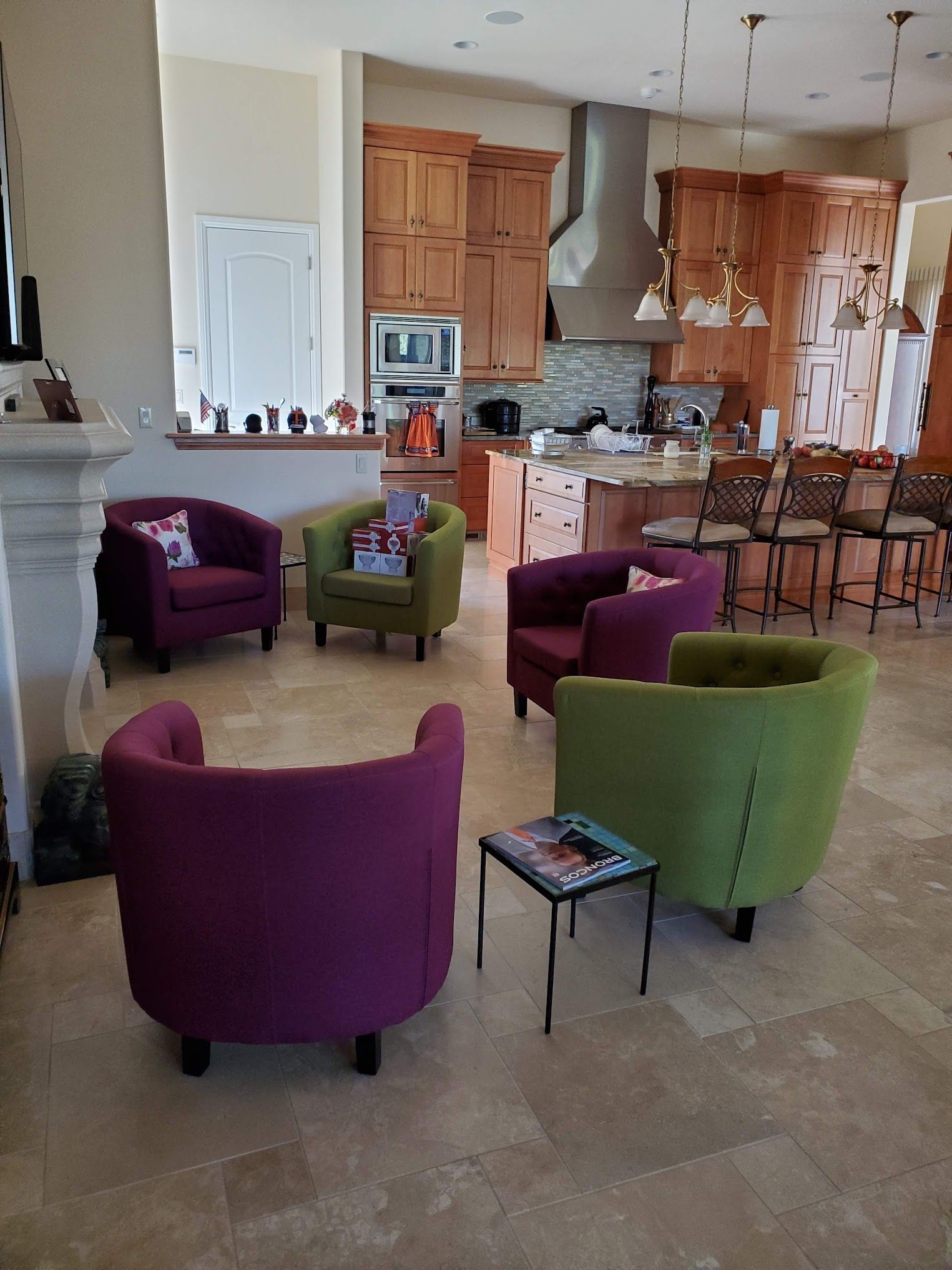 Living room with a circle of colorful chairs around a small table, near a kitchen.