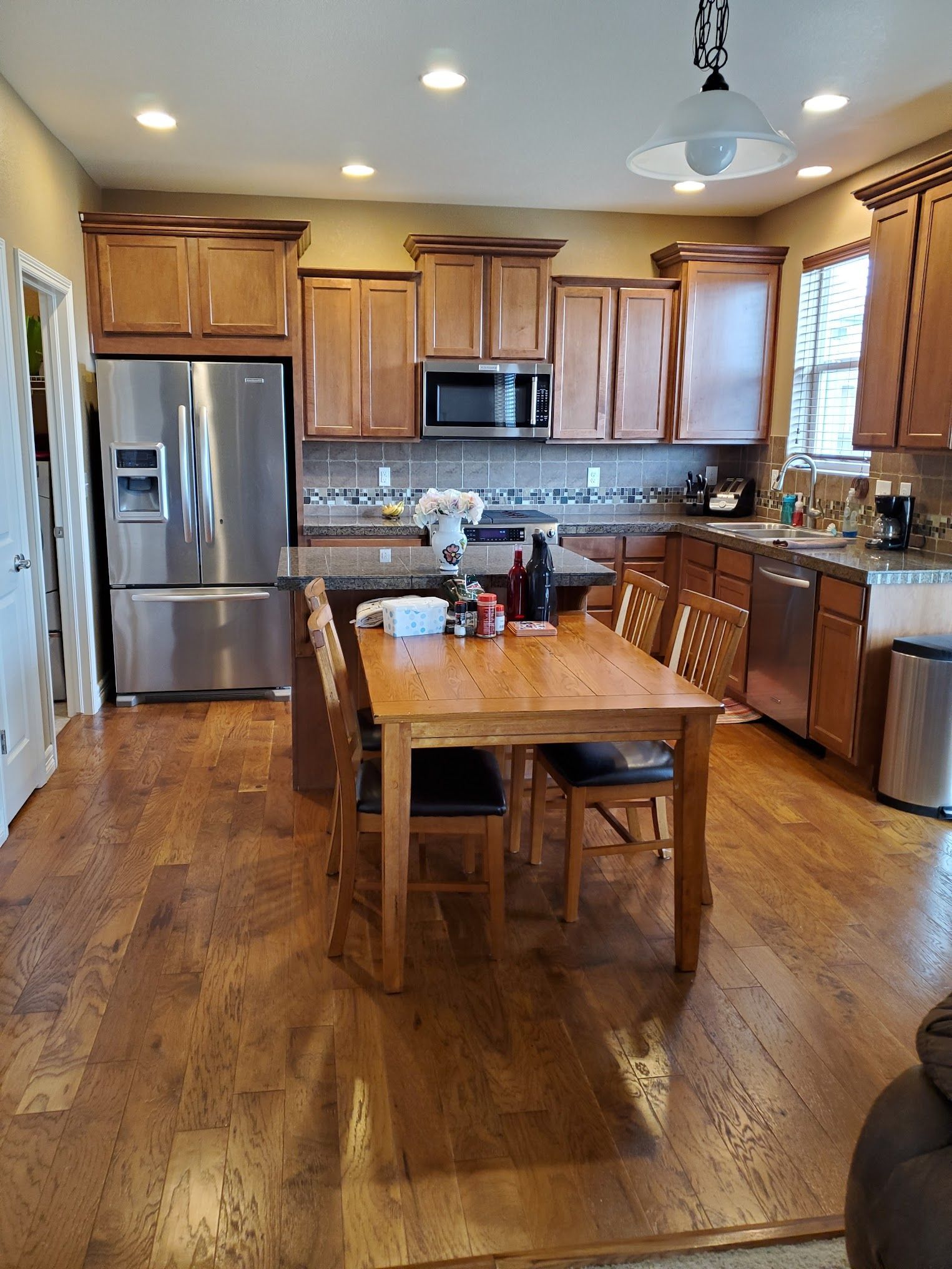 Kitchen with wood cabinets, stainless steel appliances, wood table, and chairs.