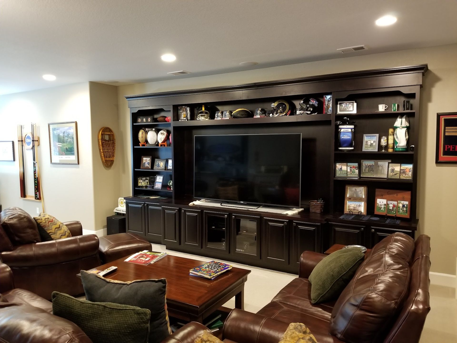 Living room with a dark wood entertainment center, leather sofas, and a coffee table.