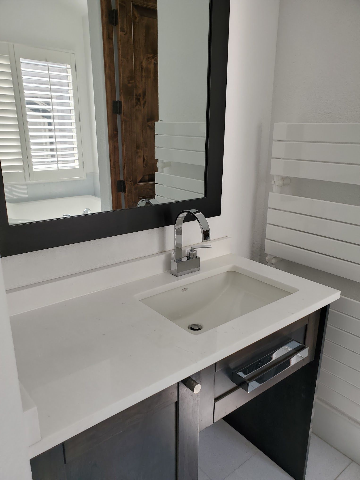 Bathroom with a white countertop, dark gray cabinet, and a silver faucet.