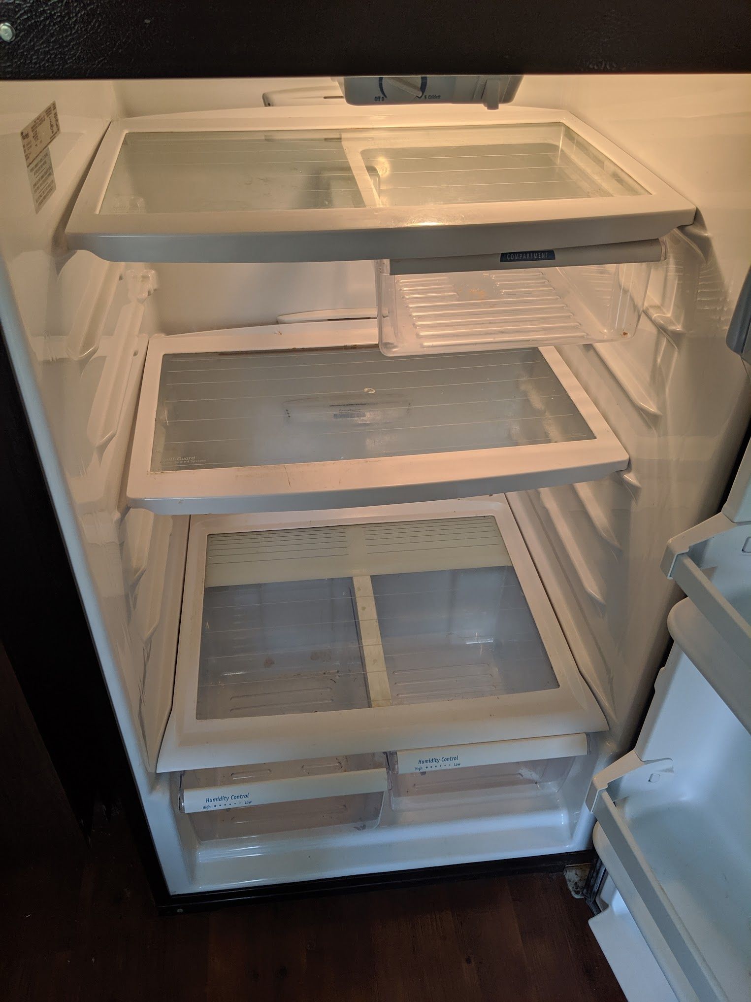 Open refrigerator interior with glass shelves, empty of food.