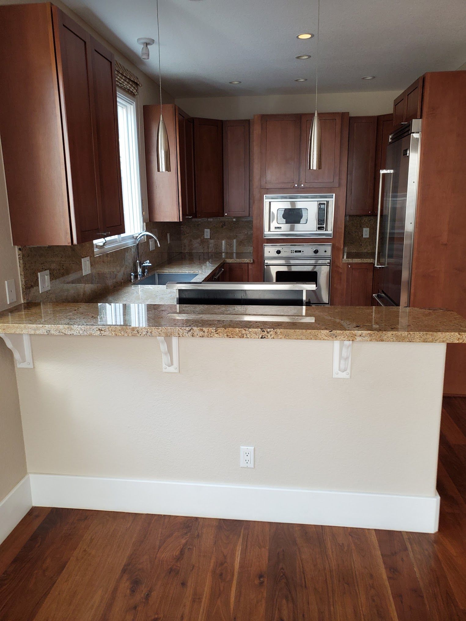 Kitchen with brown cabinets, granite countertops, breakfast bar, and stainless steel appliances.