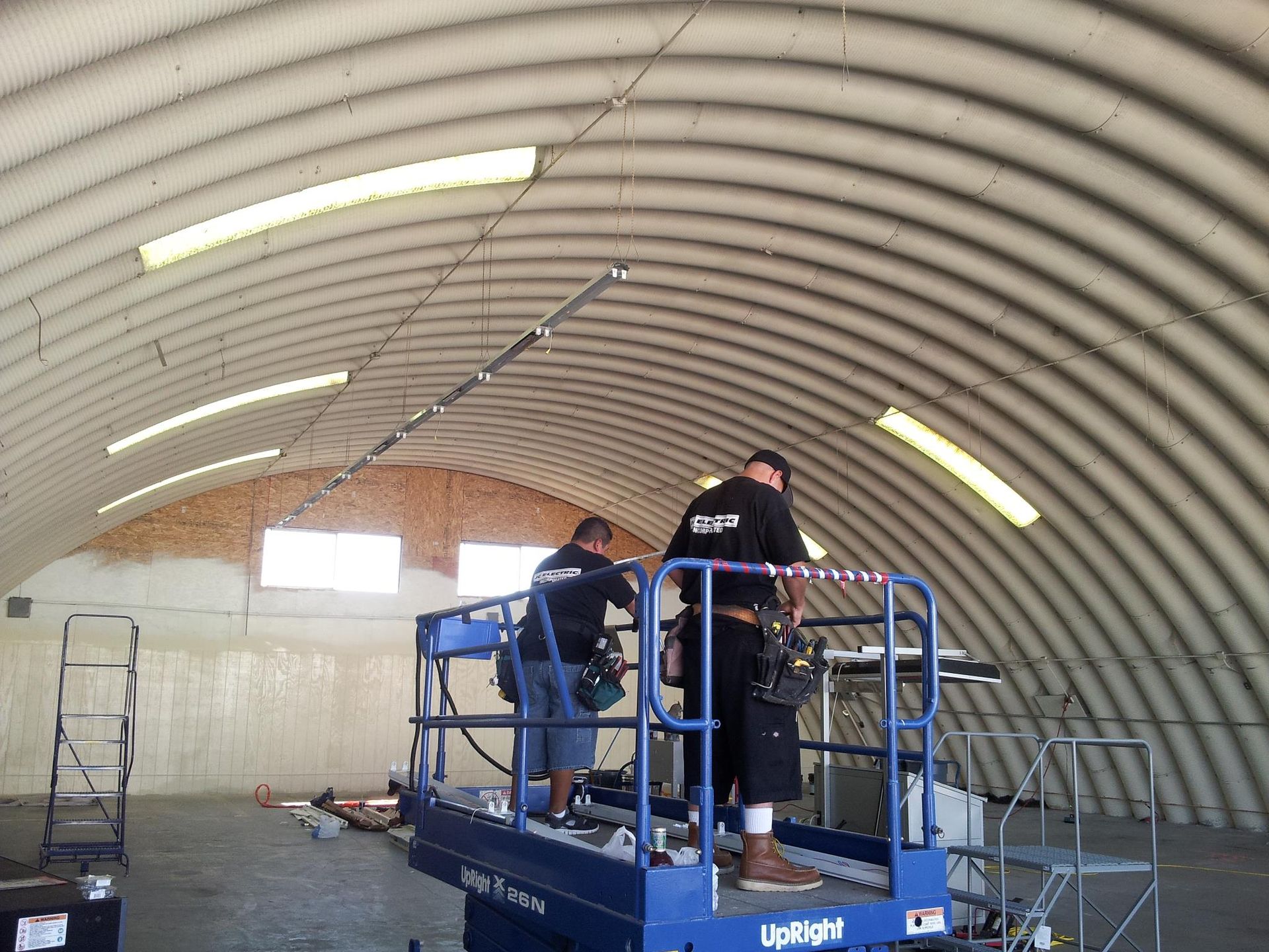 Two men are working on a lift inside of a building