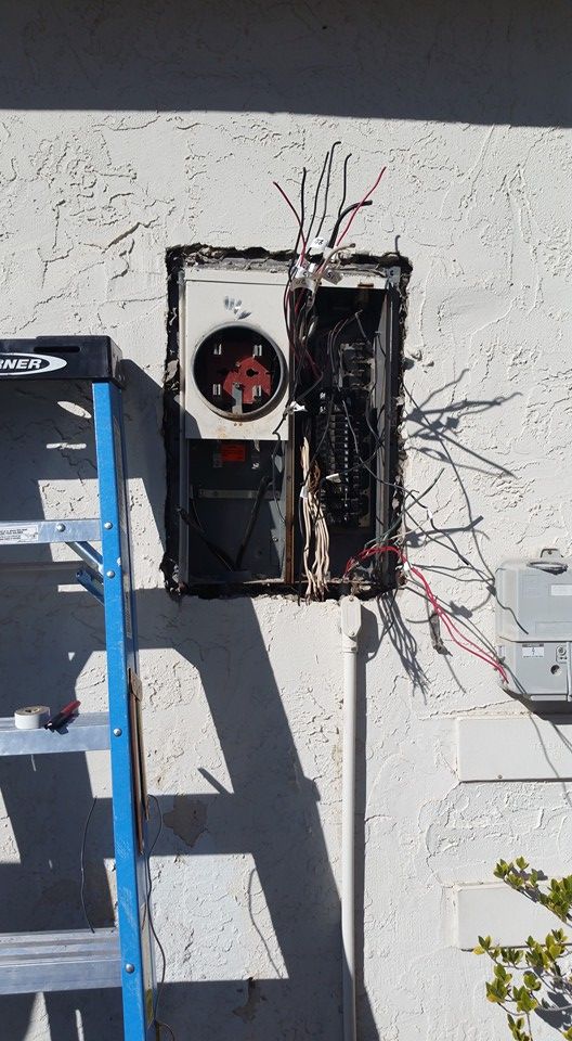 A ladder is sitting next to a broken electrical box on a wall.