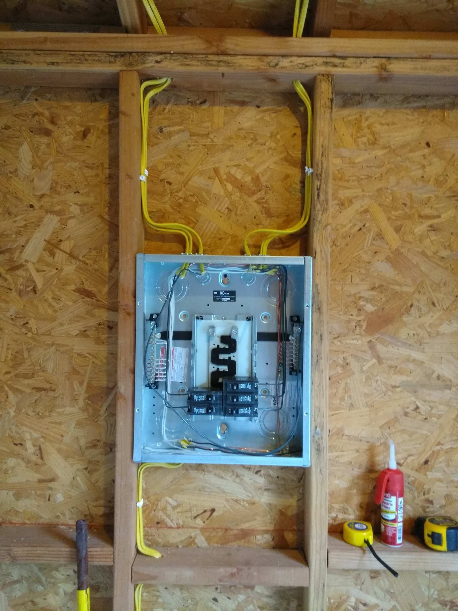 An electrical box is hanging on a wooden wall next to a ladder.