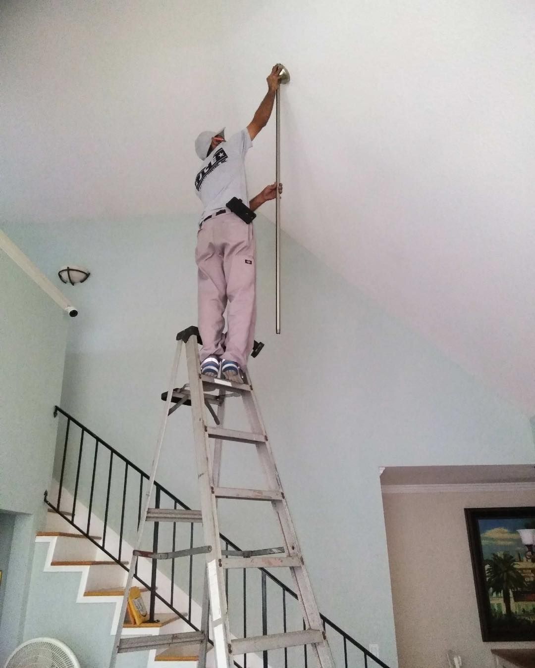 A man standing on a ladder measuring a ceiling
