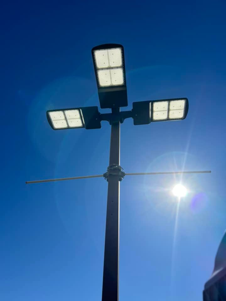A street light on a pole with the sun shining through it.