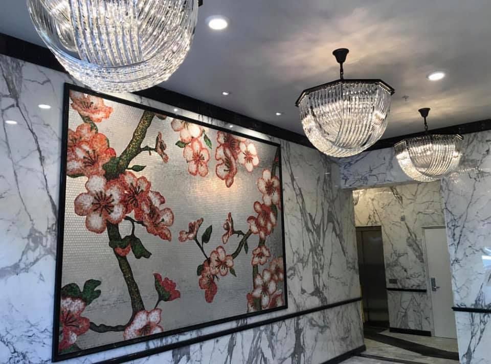 A hallway with a painting of flowers on the wall and chandeliers hanging from the ceiling.