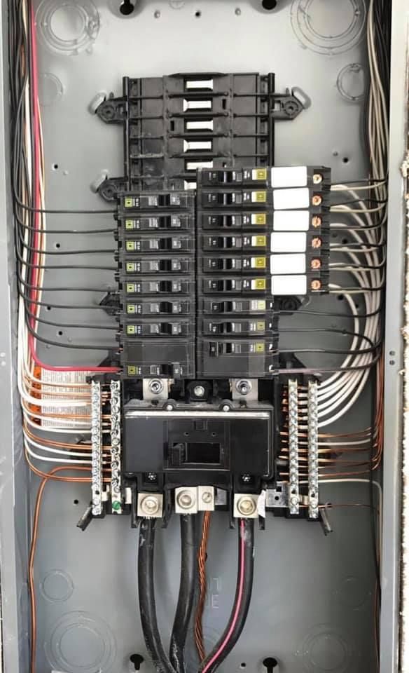 A close up of a electrical panel with a lot of wires coming out of it.