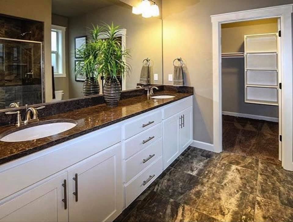 A bathroom with two sinks and a walk in closet.