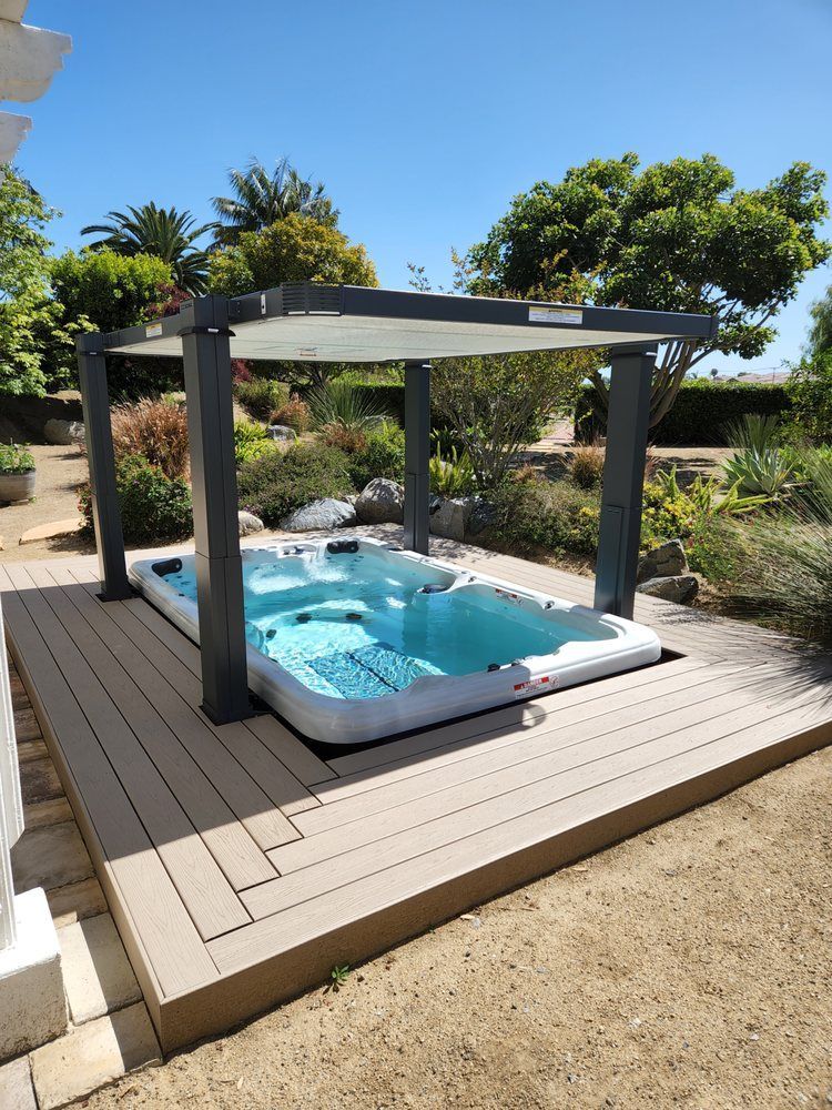 A hot tub is sitting on a wooden deck under a canopy.