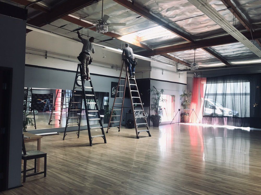 A group of people are standing on ladders in a large room.