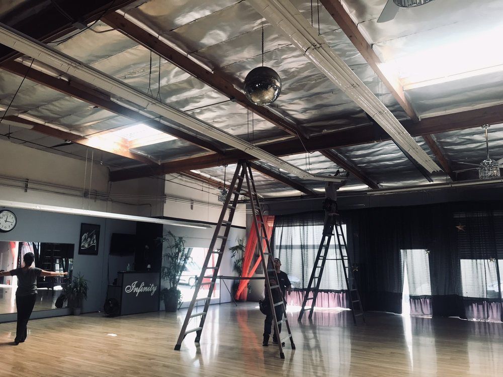 A group of people are standing on ladders in a dance studio.