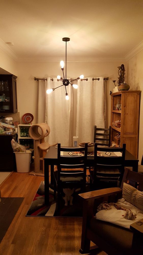 A dining room with a table and chairs and a chandelier hanging from the ceiling.