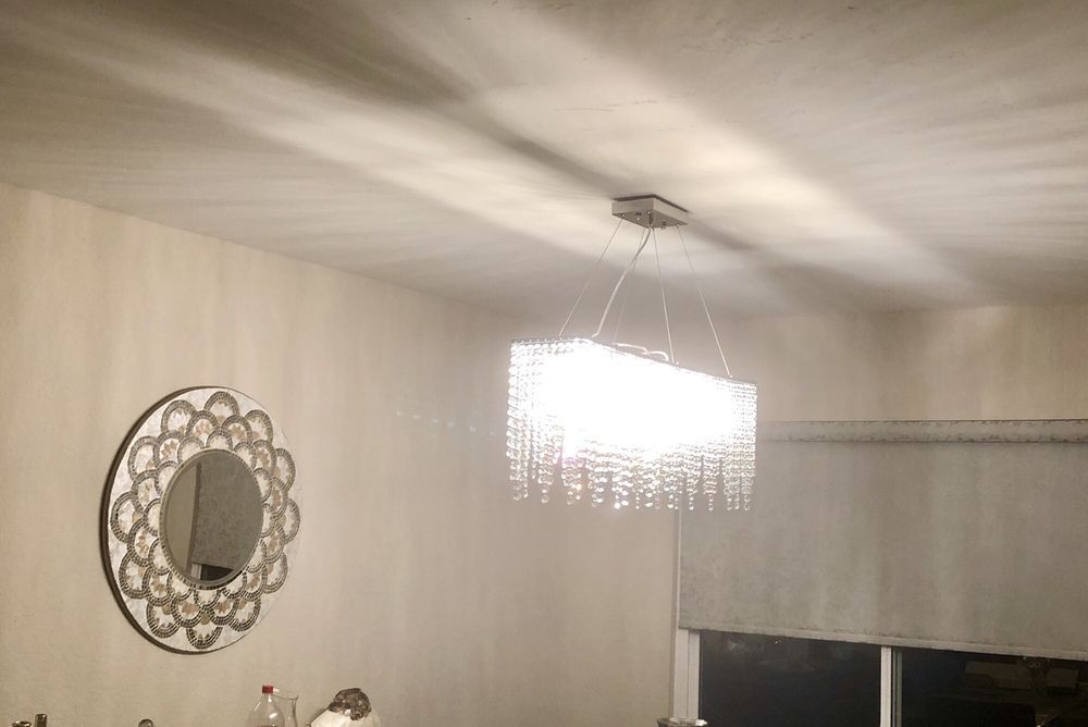 A dining room with a mirror and a chandelier hanging from the ceiling.