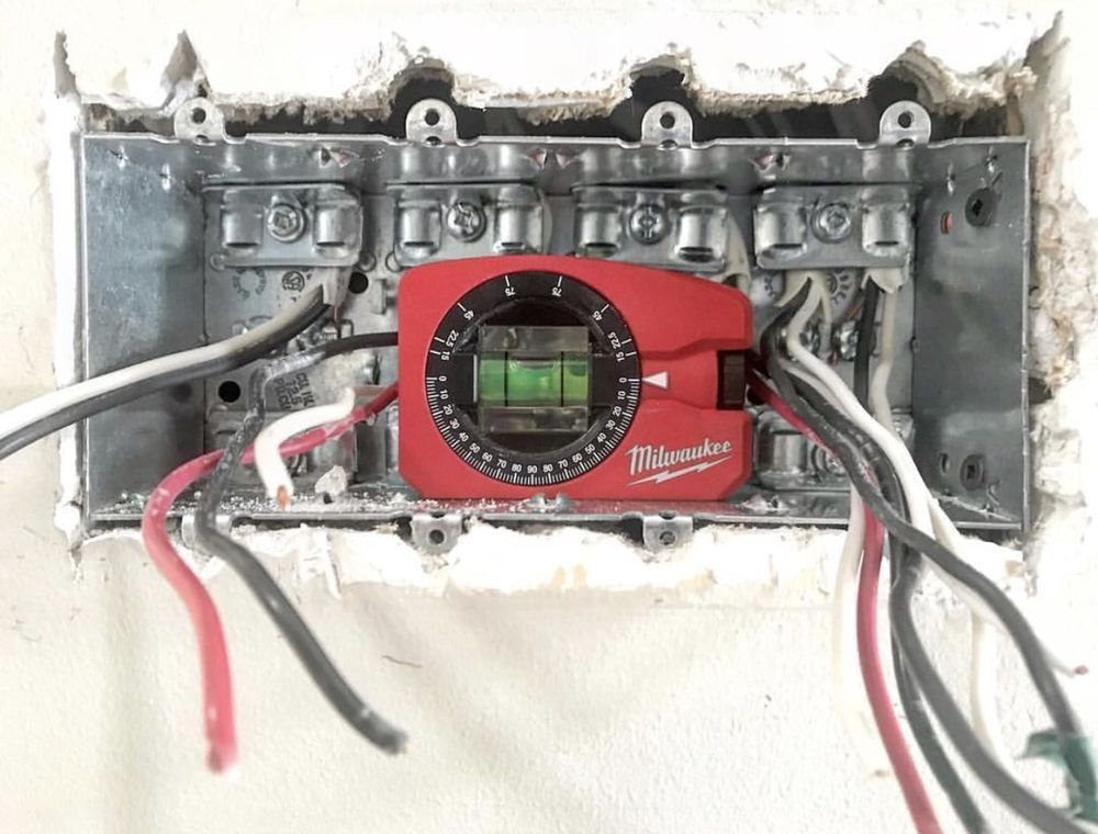 A red milwaukee level is attached to a box with wires coming out of it.