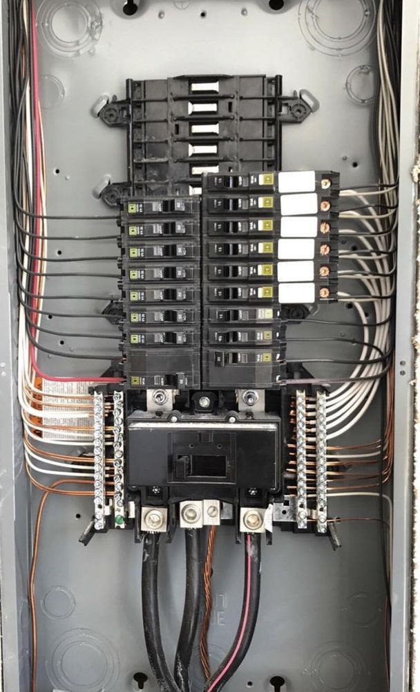 A close up of a electrical panel with a lot of wires coming out of it.