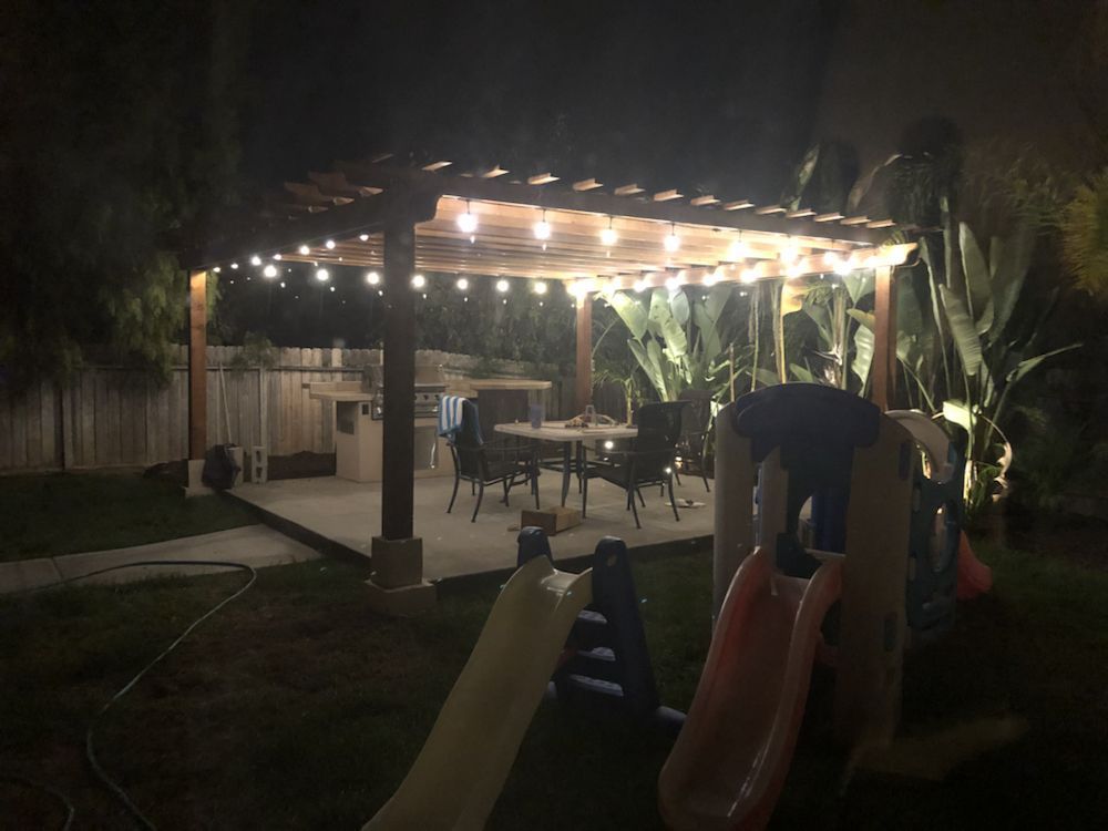 A backyard with a pergola and a slide at night.
