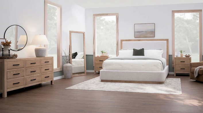 A bedroom with a bed , dresser , nightstand , mirror and rug.