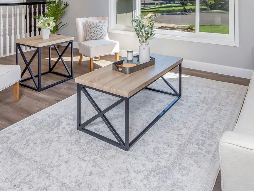 A living room with a coffee table , chairs , and a rug.