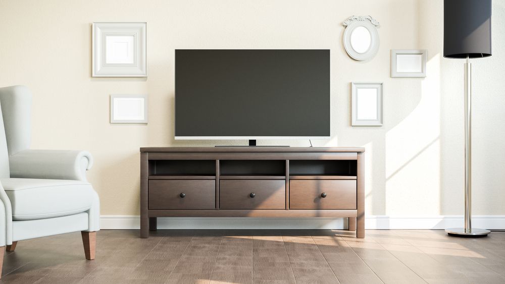 A living room with a television on a stand and a chair.