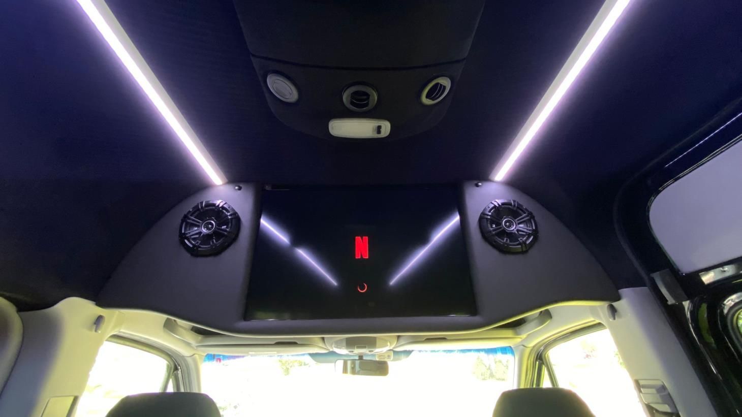 A car with a ceiling mounted tv and speakers.