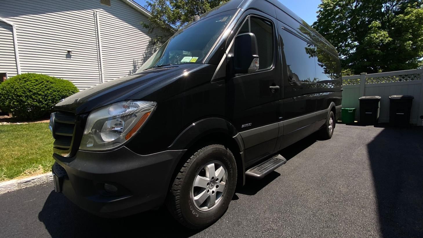 A black van is parked in a driveway in front of a house.