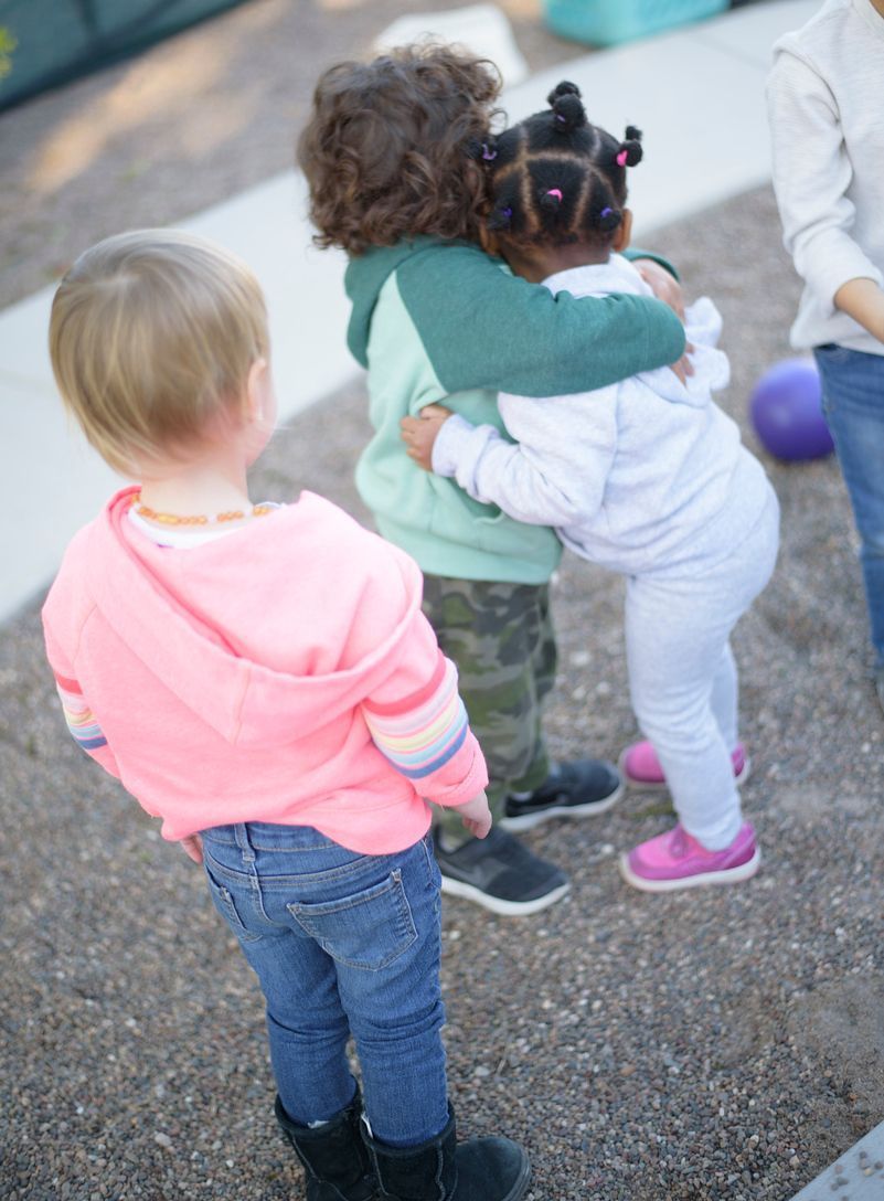 Montessori children hugging during outdoor time 