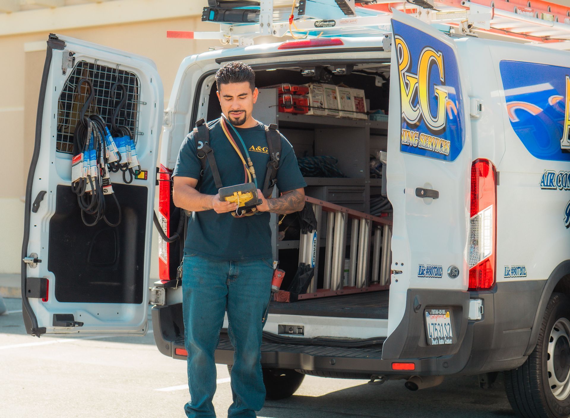 An A & G Technician  is standing in front of a van with the door open.