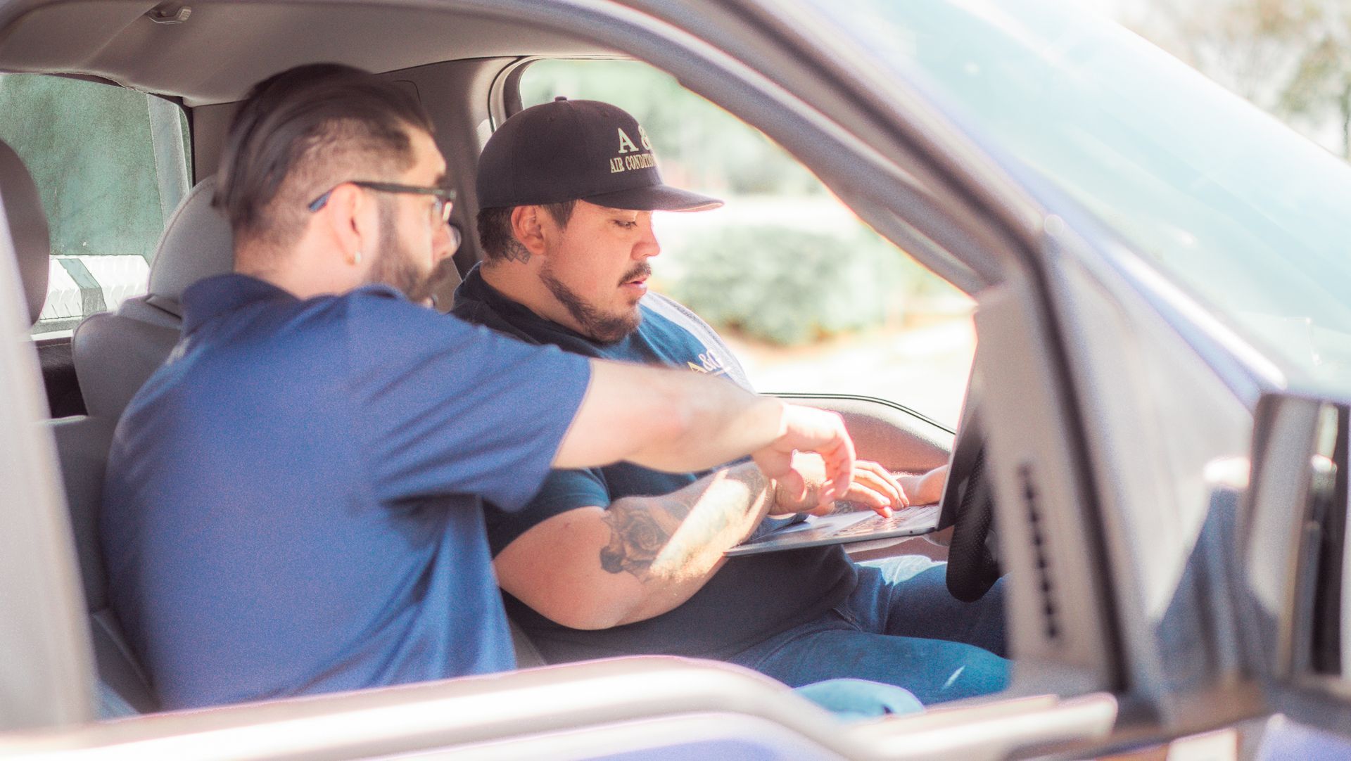 Two A & G Technician are sitting in a car looking at a tablet in San Bernardino County.