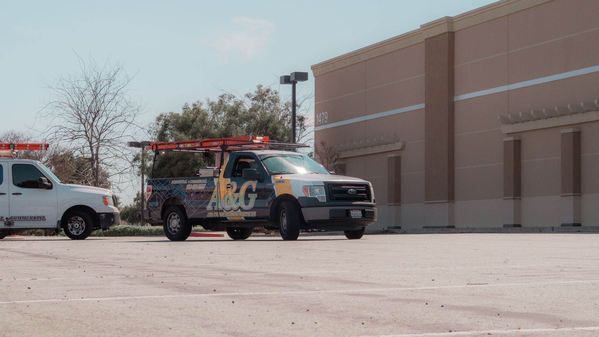 Two A & G Air Conditioning trucks are parked in a parking lot in front of a building in San Bernardino County.