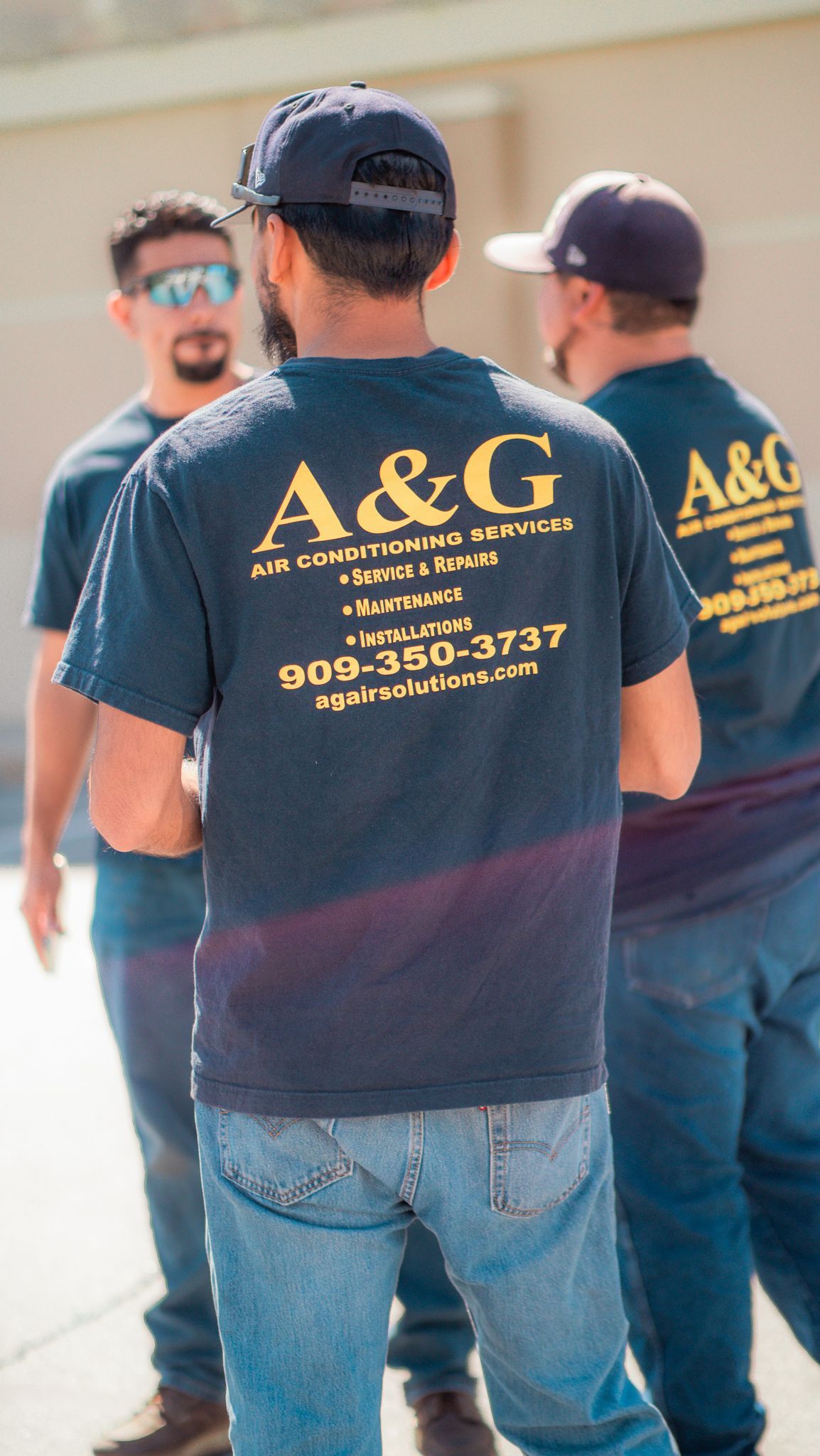 A group of A & G Technician wearing a & g shirts are standing next to each other.
