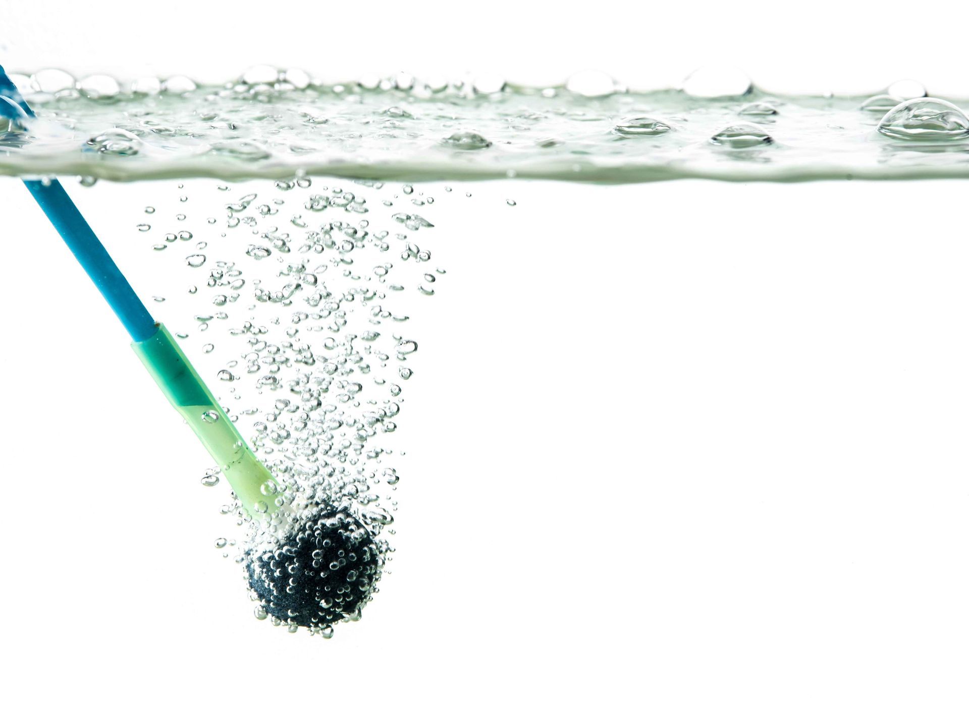 Cat reaching for a small piece of food on a white table near a window.